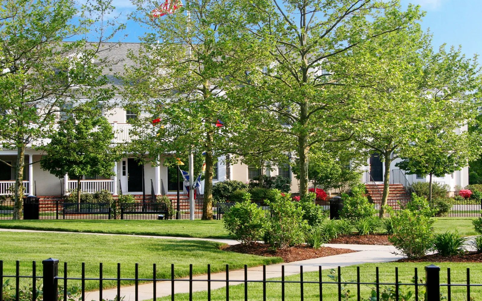 Townhomes framed by mature shade trees and iron fencing at Chapman's Reach in Quincy MA