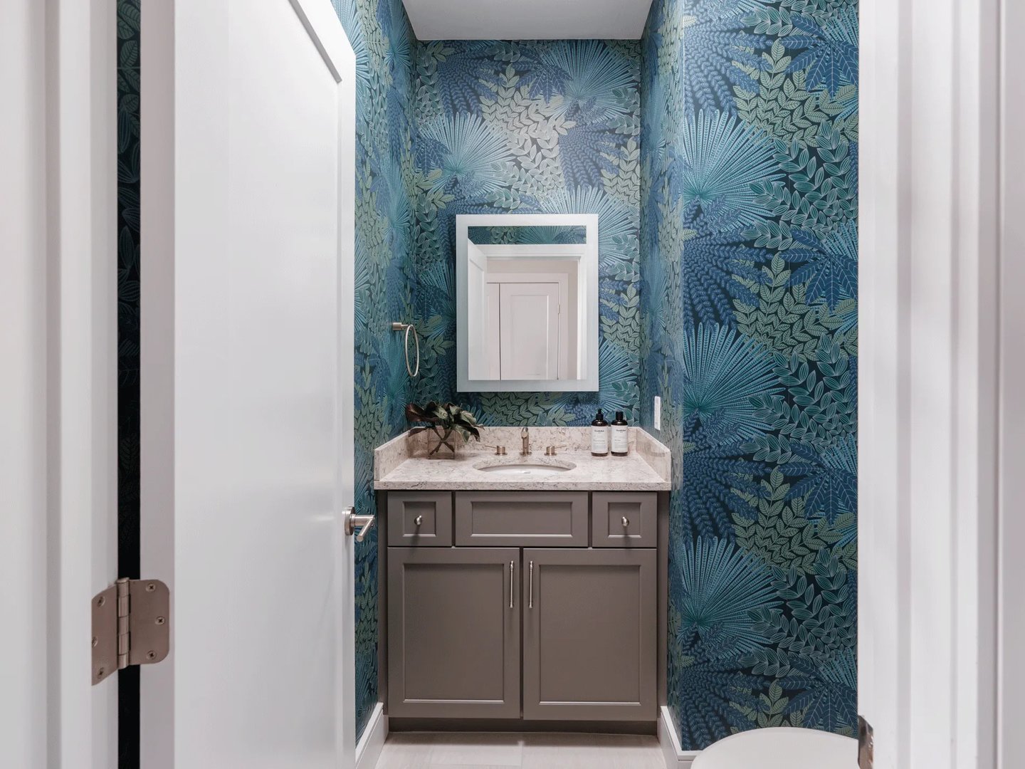 Powder room in a Larkwood townhome in Raynham MA with bold tropical leaf wallpaper