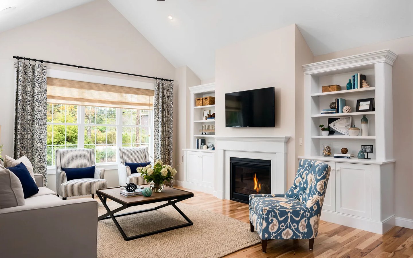 Cozy living room with fireplace and cathedral ceiling in Summer Reach model home Plymouth Massachusetts